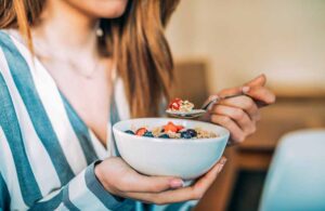 Woman eating oat and fruits bowl